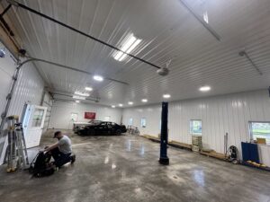 An electrician from Ardent Electric installing new lighting in a spacious garage in Erie, PA.