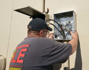An electrician installing an outdoor electrical meter box for T-Volt, Inc. Electrical Contractor in Fort Lauderdale, FL.