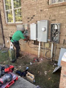 An electrician from Green Volt Electric LLC installing or repairing multiple outdoor electrical panels in Durham, NC.