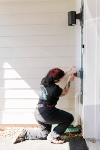 An electrician installing an outdoor electrical box or fixture on a home exterior for Common Ground Electrical in Baltimore, MD.