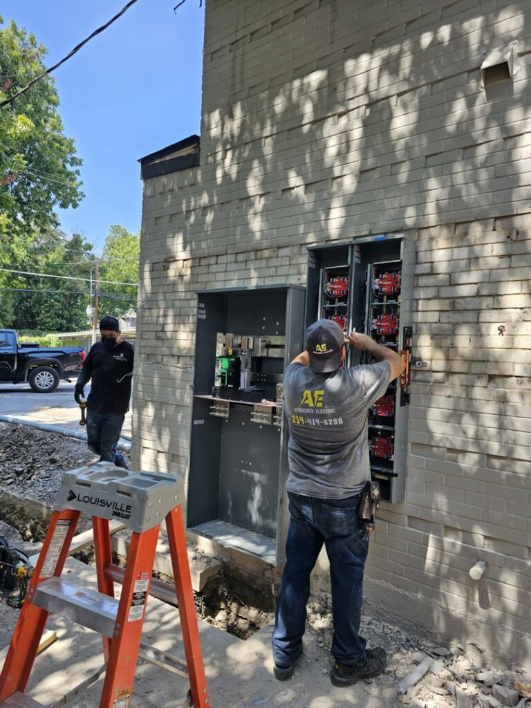 An electrician from Acevedo's Electric installing an outdoor electrical panel on a brick building in Dallas, TX.
