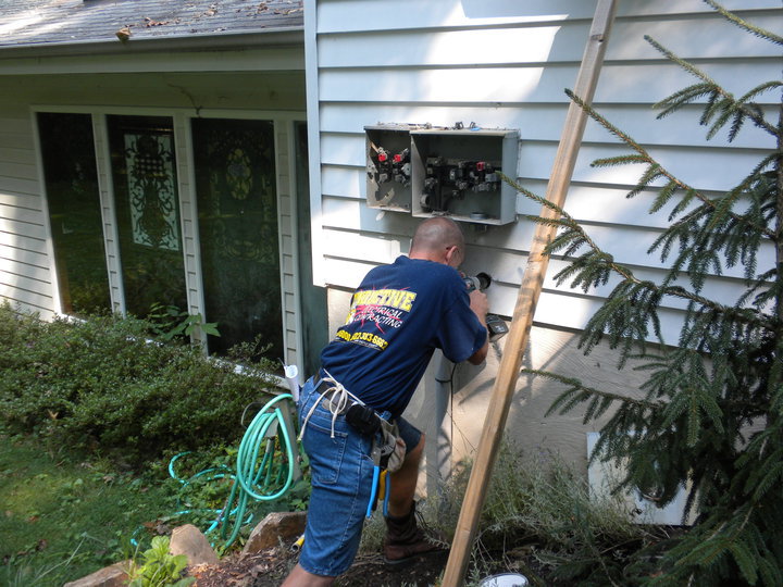 An electrician from Conductive Electrical Contracting installing an outdoor electrical panel on a house in Smyrna, DE.