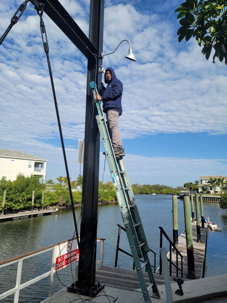 An electrician on a ladder installing an outdoor light fixture or camera by Wirenut Technologies LLC in Brandon, FL