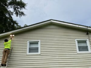 An electrician from High Electrical installing an outdoor floodlight on a ladder in Atlanta, GA.