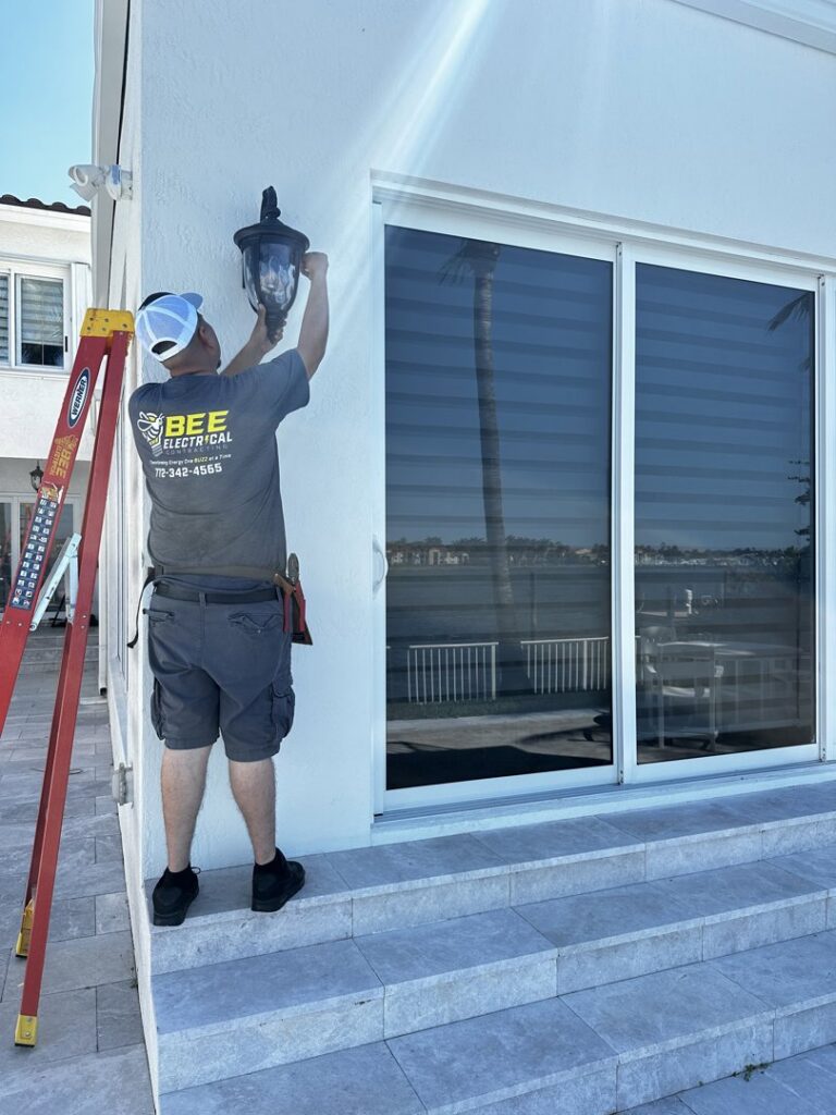 An electrician from Bee Electrical Contracting installing an outdoor light fixture on a house in Port Saint Lucie, FL.