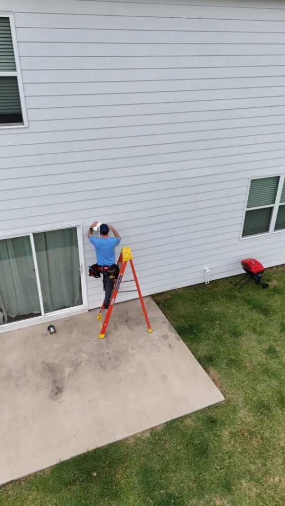 An electrician from Dr. Sparky on a ladder installing an outdoor light fixture on a house in Nashville, TN