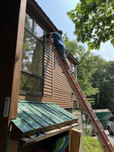 An electrician on a ladder installing an outdoor light fixture for EO Ross Electrical Contractors Inc. in Springfield, MA.