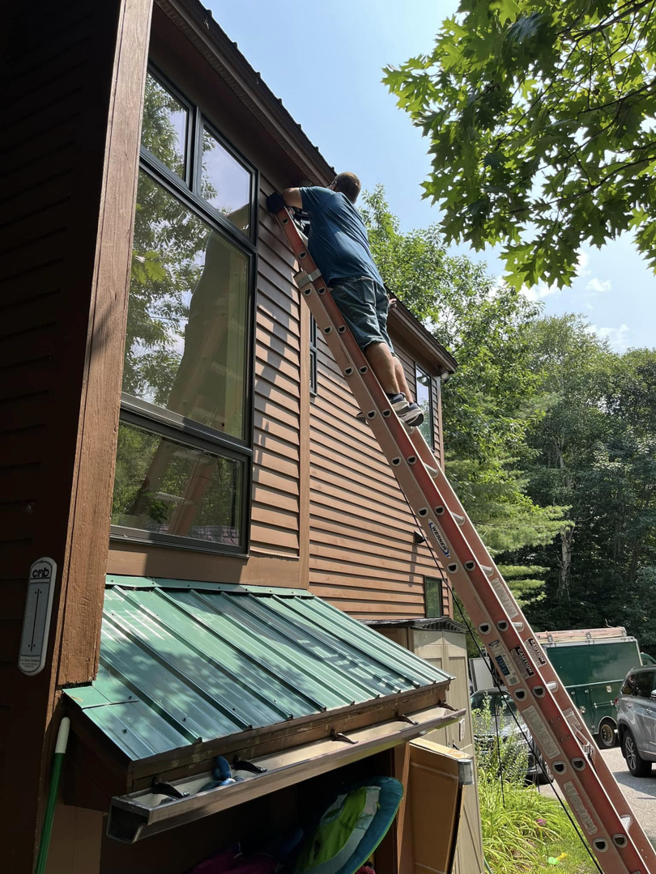 An electrician on a ladder installing an outdoor light fixture for EO Ross Electrical Contractors Inc. in Springfield, MA.