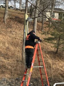 An electrician from Moser Electric installing an outdoor light fixture on a wooden pole in Wisconsin Rapids, WI.