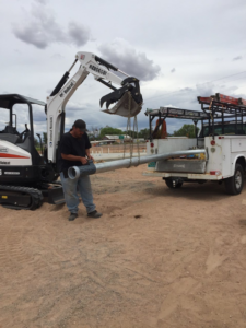 An electrician installing an outdoor light pole with heavy equipment for O'Dell Electrical Services in Albuquerque, NM.