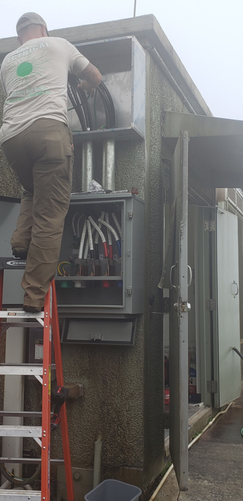 An electrician on a ladder installing wiring in an outdoor electrical box for F & L Electrical, LLC in Clemmons, NC.