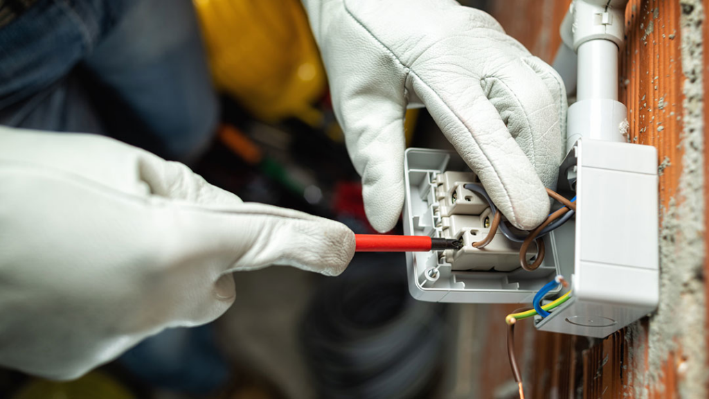 An electrician installing an electrical outlet with a screwdriver for All American Pro Electric LLC in Cedar Creek, TX.