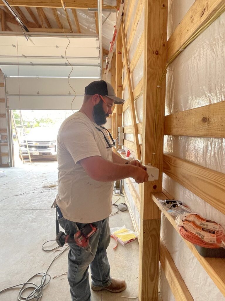 An electrician from P.H. Electric installing an electrical outlet on a wooden stud wall in Soulsbyville, CA.