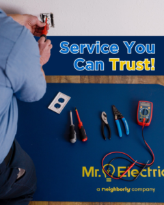 An electrician installing an electrical outlet with tools on a branded mat for Mr. Electric of Rogers in Rogers, AR.