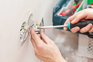 An electrician installing an electrical outlet with a screwdriver for Reliable Electric in Olympia, WA.