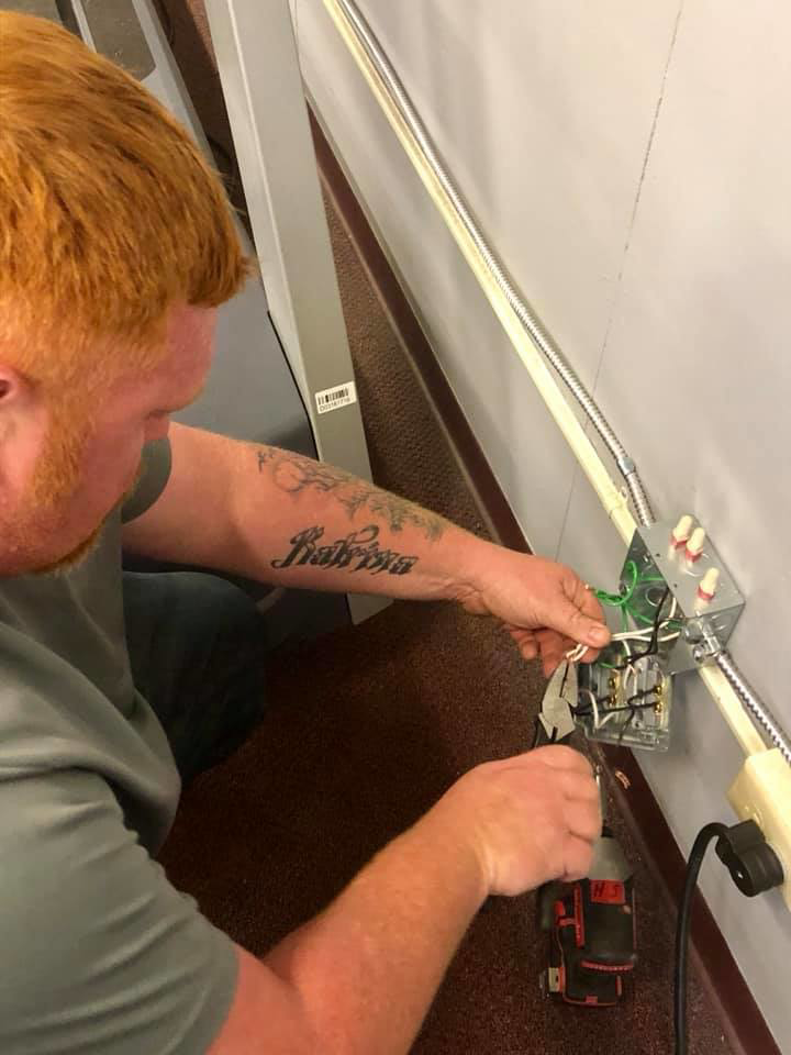 An electrician from Swaim's Electrical Services installing new outlet wiring on a wall in Wilmington, NC.