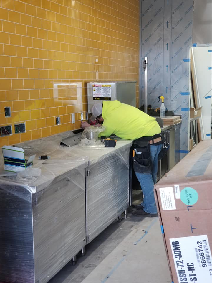 An electrician installing electrical outlets and fixtures above a counter for 2 Phase Electric LLC in Barnesville, MN.