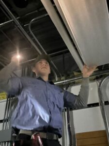 An electrician installing or adjusting an overhead light fixture at Three Rivers Electric in Fort Wayne, IN.