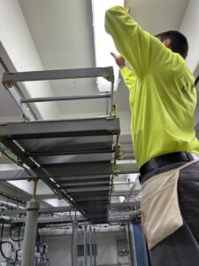 An electrician installing or maintaining overhead lighting and wiring in a commercial space by Top Tier Electrical Services LLC in Knoxville, TN