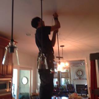 An electrician from Barrios Electric LLC installing pendant lights in a kitchen in Norwalk, CT.