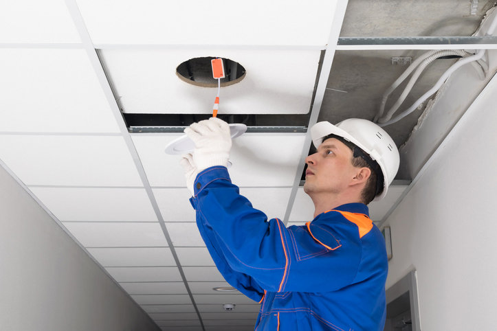An electrician in a hard hat installing a recessed light fixture in a ceiling for BrotherlyLove Electric LLC in Houston, TX.