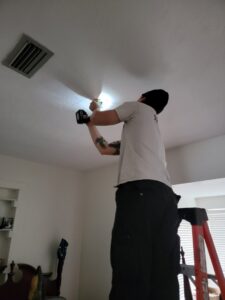 An electrician from Heck Electric, LLC in Everett, WA, installing a recessed light fixture in a ceiling