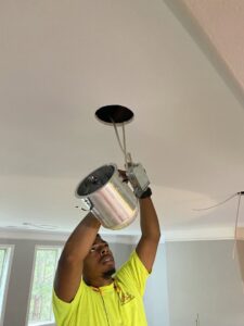 An electrician from High Electrical installing a recessed light fixture in a ceiling in Atlanta, GA.