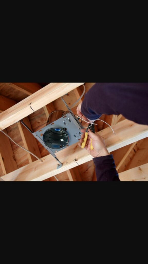 An electrician's hands installing wiring into a recessed light fixture in a wooden ceiling by My A Plus Electric SA in San Antonio, TX