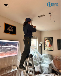 An electrician installing recessed lighting in a home, demonstrating expert service from AO Electric Inc. in Sacramento, CA.