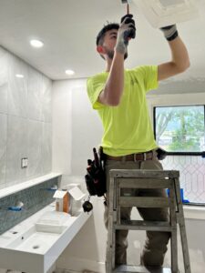 An electrician on a step ladder installing a recessed light fixture in a bathroom for Buckeye Electric of Upper Arlington, LLC in Columbus, OH.