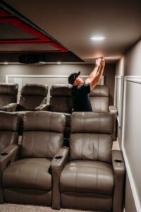 An electrician from Arnold Electrical Repair & Installation installing recessed lighting in a home theater room in Chicago, IL.