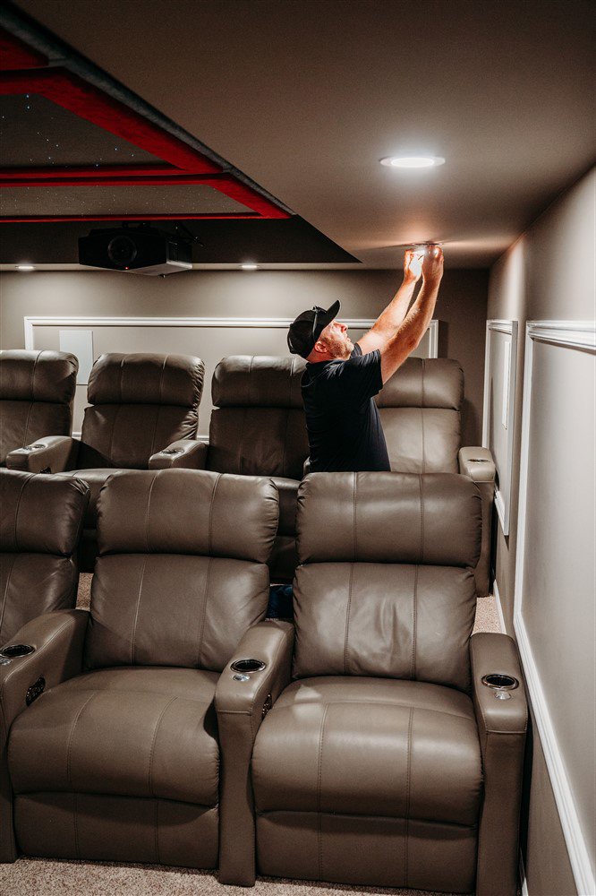 An electrician from Arnold Electrical Repair & Installation installing recessed lighting in a home theater room in Chicago, IL.
