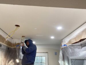 An electrician from Intel-electric installing recessed lighting fixtures in a ceiling in Anchorage, AK