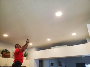 An electrician on a ladder installing recessed lighting in a ceiling, a service by Small Jobs Electric in Tampa, FL.