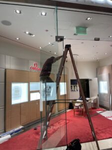 An electrician on a ladder installing ceiling lighting in a retail store for Flowers Electric in Aurora, CO.