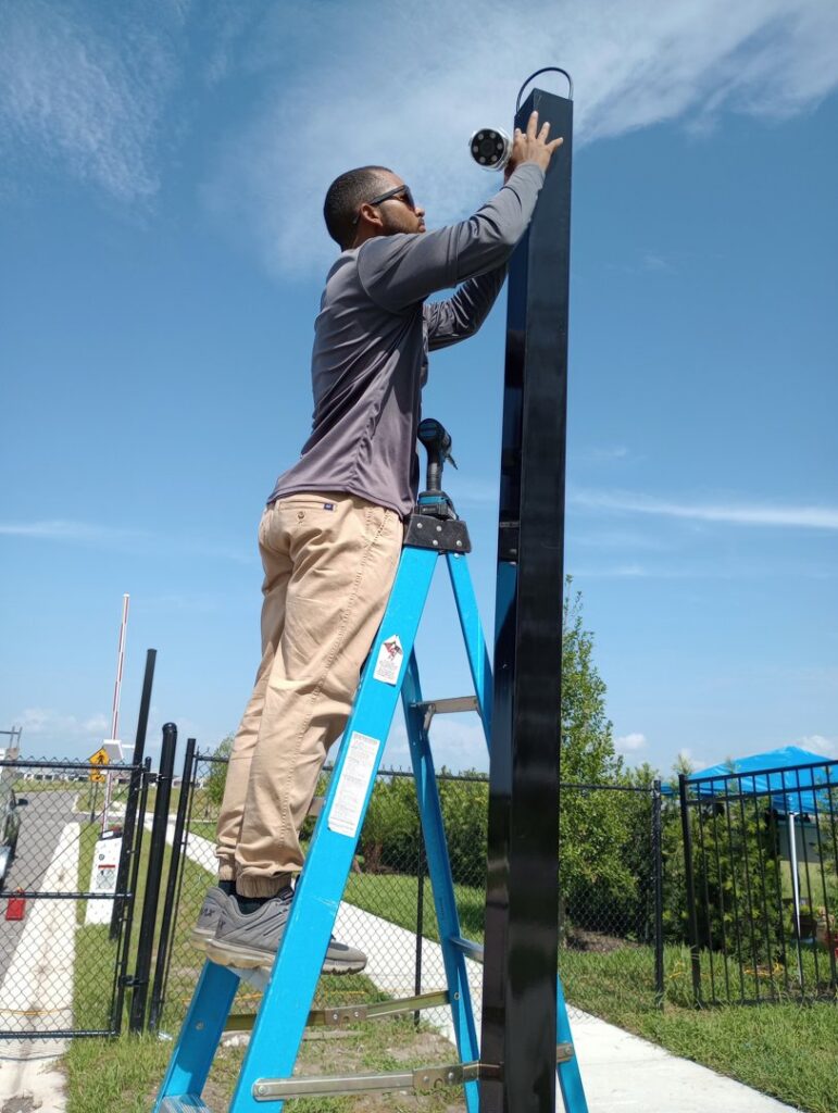 An electrician installing a security camera on a pole for Wirenut Technologies LLC in Brandon, FL.