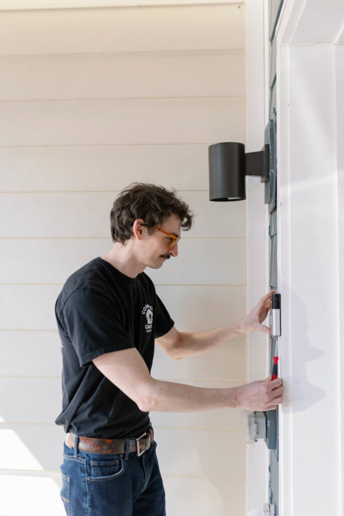 An electrician installing a smart doorbell system on a home exterior for Common Ground Electrical in Baltimore, MD.