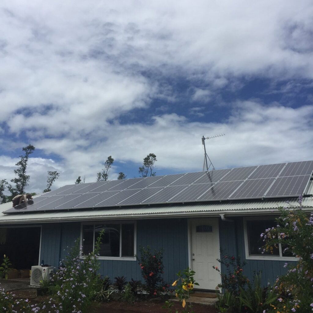 An electrician installing solar panels on a residential roof for Big Island Electric & Solar in Hilo, HI