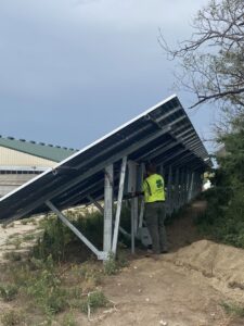 An electrician from McPhillips Electric LLC in Columbus, NE, installing solar panels on a ground-mounted system.