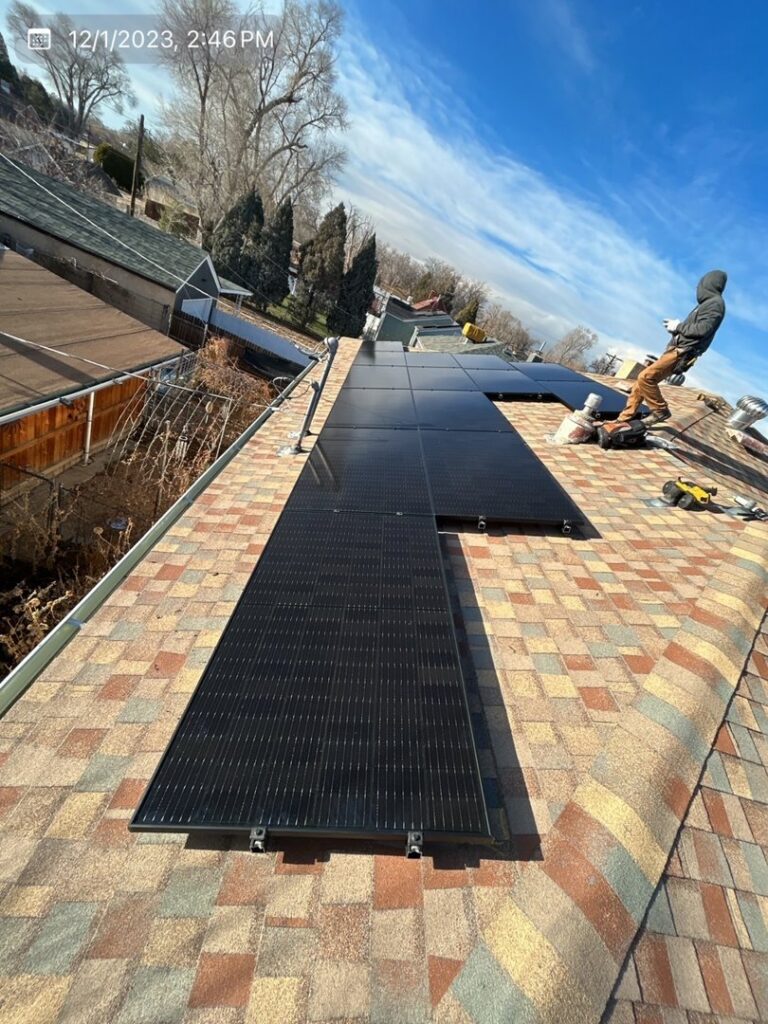 An electrician installing solar panels on a residential rooftop, demonstrating work by Pueblo Electrics, Inc. in Pueblo, CO.