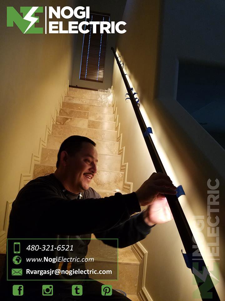An electrician from Nogi Electric LLC installing LED strip lighting along a staircase railing in Mesa, AZ.