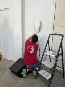 An electrician installing a Tesla EV charger in a garage for Goal Electric LLC in West Valley City, UT.