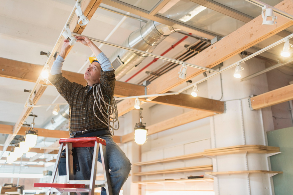 An electrician installing track lighting in a commercial space for Crawford Electric Co. LLC in West Columbia, SC.
