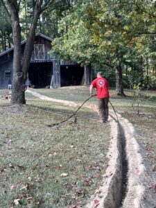 An electrician installing underground electrical cable in a trench for Spencer Electric in Hopkins, MN.