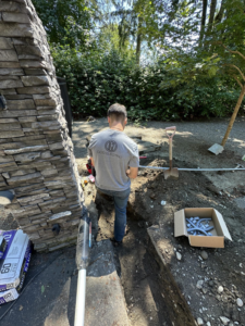 An electrician from OCD Electric installing underground electrical conduit in a trench in Spokane, WA.