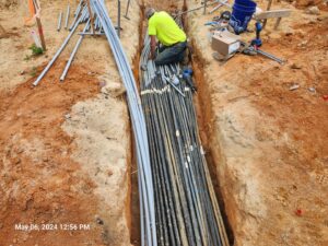 An electrician installing underground electrical conduits and cables in a trench for TOTAL Electric LLC in Fayetteville, NC.