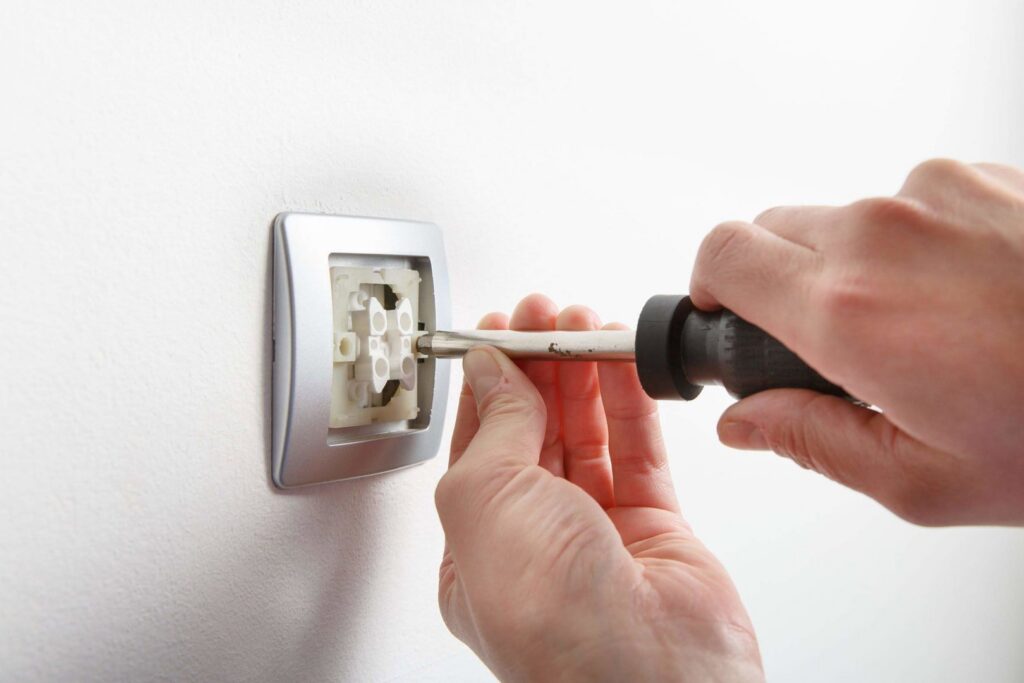 An electrician installing a wall electrical outlet with a screwdriver for Polsley Electric Company in Omaha, NE