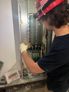 An electrician from Camsan Inc. Electrical Contractors installing wires inside an electrical panel in Stamford, CT.