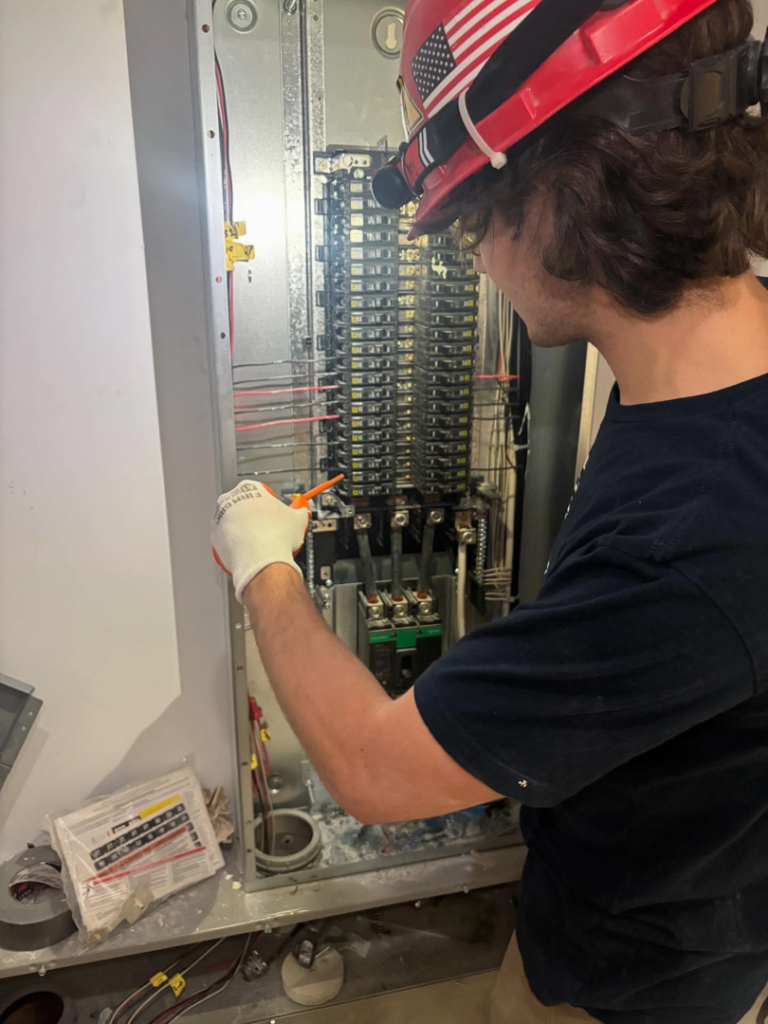 An electrician from Camsan Inc. Electrical Contractors installing wires inside an electrical panel in Stamford, CT.
