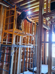 An electrician on scaffolding installing new wiring in a framed building for Haddad Electric LLC in Jersey City, NJ.